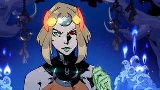 Melinoe frowns at the camera; a blonde demi-god with one red eye and one green. She holds up a spectral hand.