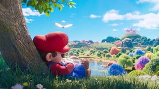 Shot from The Super Mario Galaxy Movie trailer showing Mario snoozing under a tree on a hillside overlooking the Mushroom Kingdom.